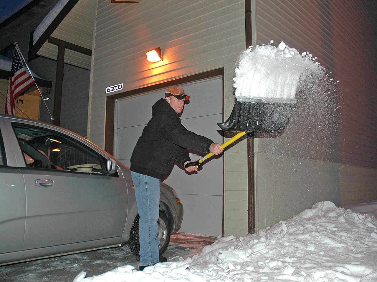 Mitarbeiter räumt Schnee vor einem Hauseingang